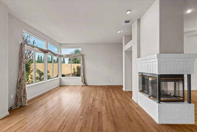 an empty room with wooden floor and fan