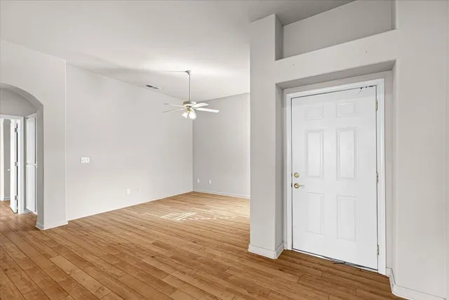 a view of an empty room with wooden floor fireplace and a window