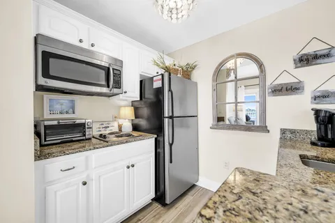 a kitchen with stainless steel appliances granite countertop a refrigerator a stove and a sink with wooden floor