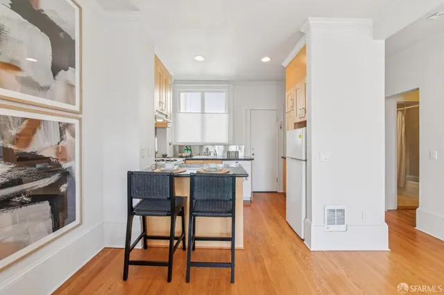 a kitchen with stainless steel appliances kitchen island granite countertop a refrigerator a stove a microwave oven with white cabinets and wooden floor