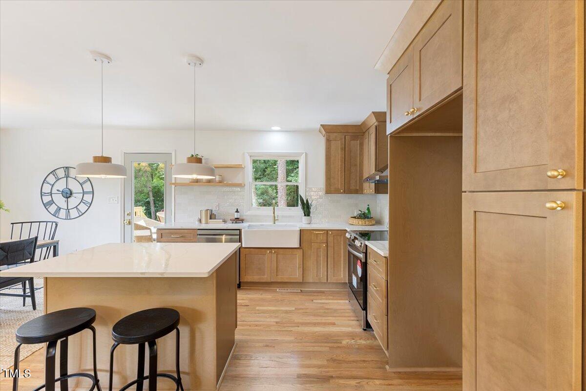 134 Radcliff Circle Durham, NC 27713 - Photo 11 of 37 a kitchen with kitchen island granite countertop a refrigerator a stove a sink and white cabinets with wooden floor