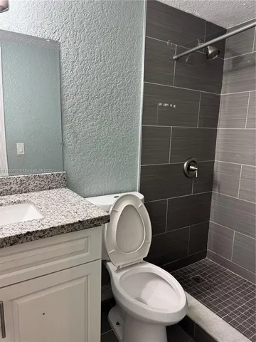 a bathroom with a granite countertop toilet a sink and a mirror