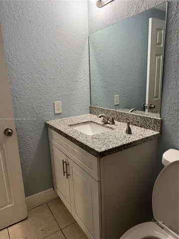 a bathroom with a granite countertop sink and a toilet