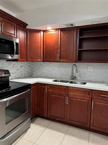 a kitchen with stainless steel appliances granite countertop wooden cabinets a stove and a sink