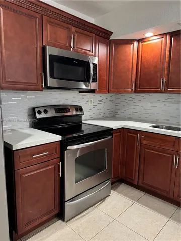 a kitchen with granite countertop wood cabinets stainless steel appliances and a window