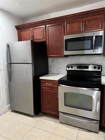 a kitchen with granite countertop white cabinets and refrigerator