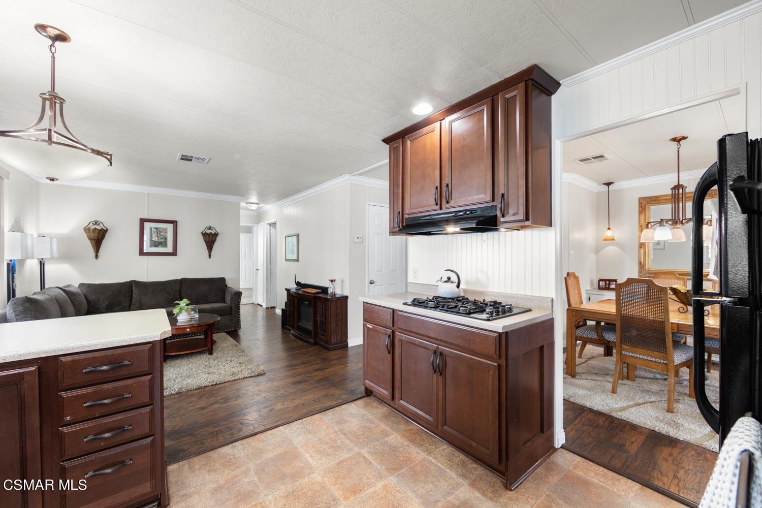 195 Tierra Rejada Road, Unit 157 Simi Valley, CA 93065 - Photo 13 of 27 a kitchen with stainless steel appliances granite countertop a stove top oven a sink dishwasher a dining table and chairs with wooden floor
