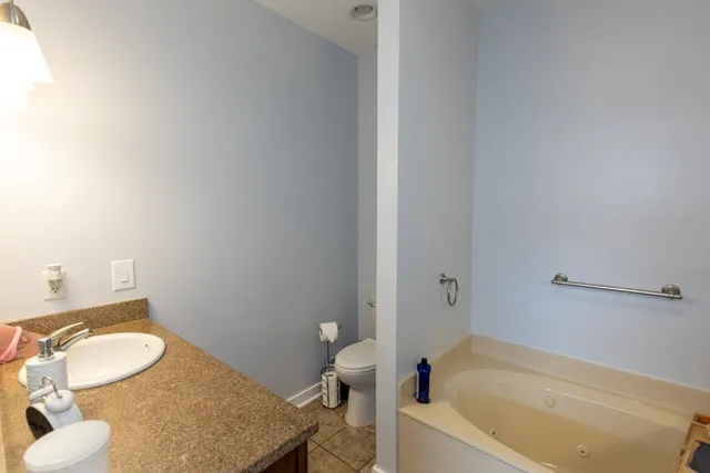 a bathroom with a granite countertop bathtub sink vanity mirror and toilet