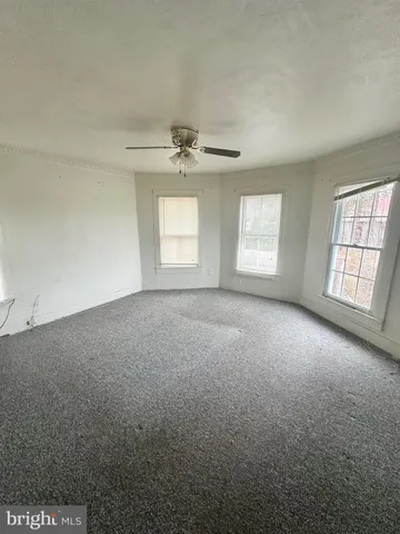 an empty room with windows and ceiling fan