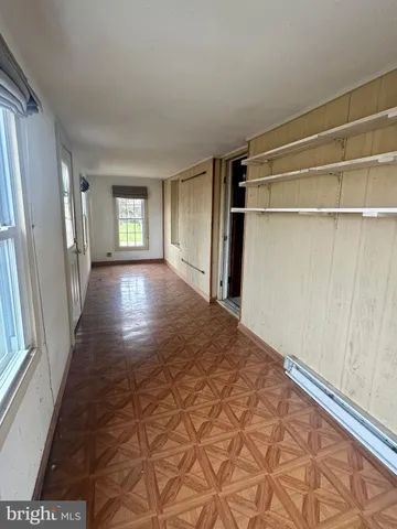 a view of empty room with wooden floor and window