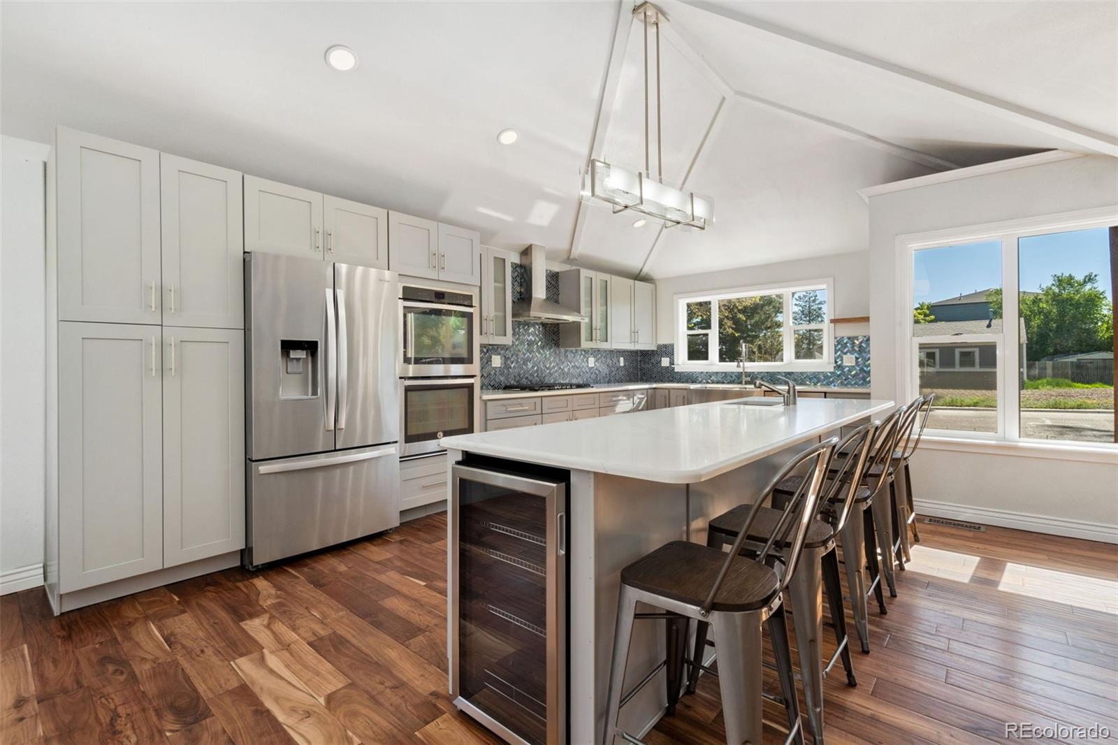 4545 Ingalls Street Wheat Ridge, CO 80033 - Photo 11 of 30 a kitchen with stainless steel appliances granite countertop a kitchen island a stove a refrigerator a sink a dining table and chairs with wooden floor