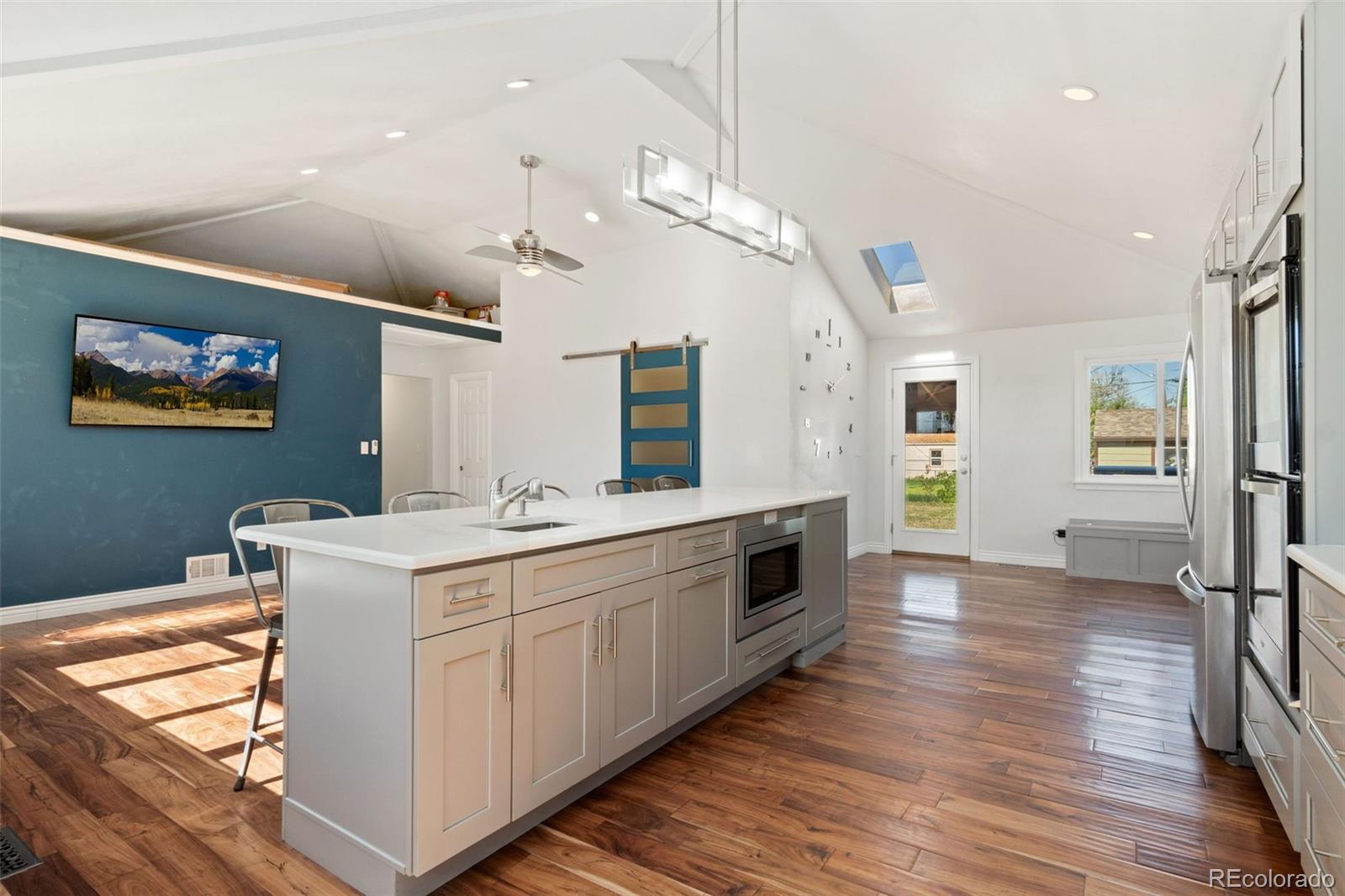 4545 Ingalls Street Wheat Ridge, CO 80033 - Photo 12 of 30 a large kitchen with kitchen island a stove a sink dishwasher and a dining table with wooden floor