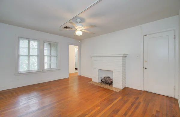 an empty room with wooden floor fireplace and windows