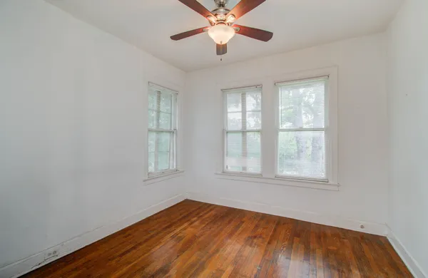 an empty room with wooden floor closet and windows