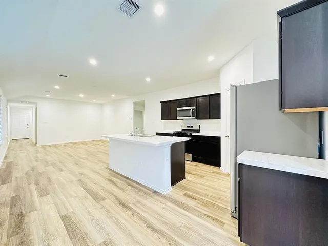 a large white kitchen with kitchen island a sink dishwasher a stove a refrigerator and a oven with wooden floor