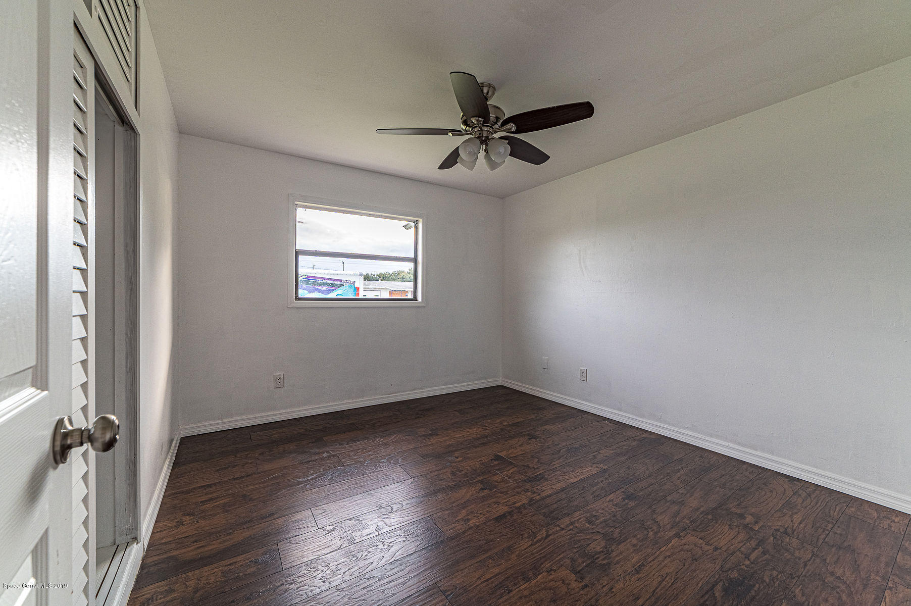 496 Seacrest Avenue Merritt Island, FL 32952 - Photo 24 of 33 an empty room with wooden floor fan and windows