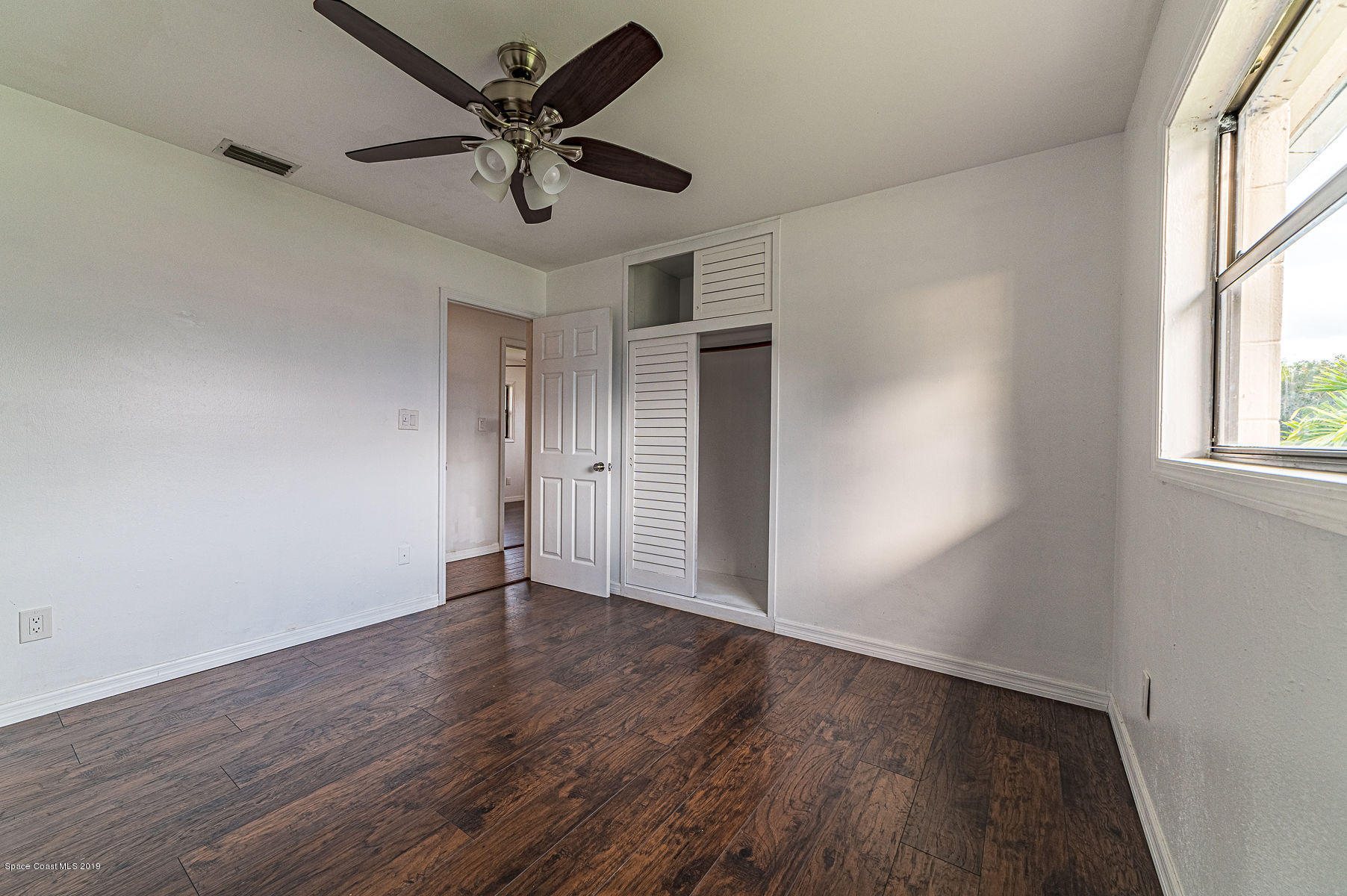 496 Seacrest Avenue Merritt Island, FL 32952 - Photo 25 of 33 an empty room with wooden floor and windows