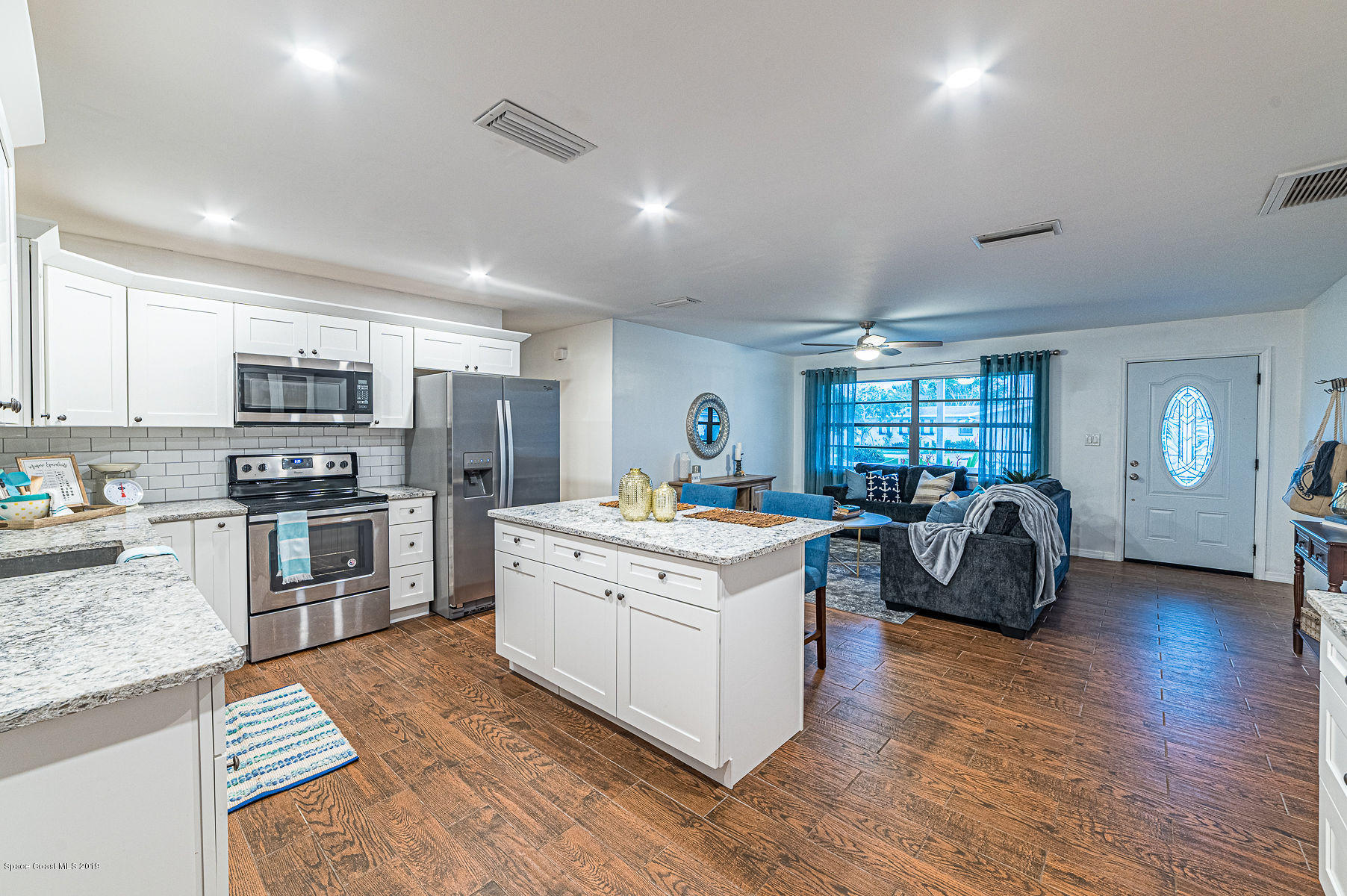496 Seacrest Avenue Merritt Island, FL 32952 - Photo 10 of 33 a kitchen with kitchen island granite countertop a stove top oven a sink dishwasher a dining table and chairs with wooden floor