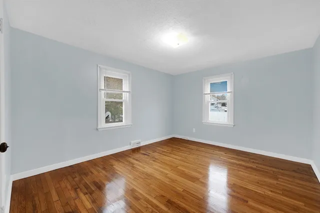 a view of a big room with wooden floor and windows
