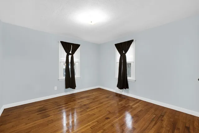 an empty room with wooden floor and mirror