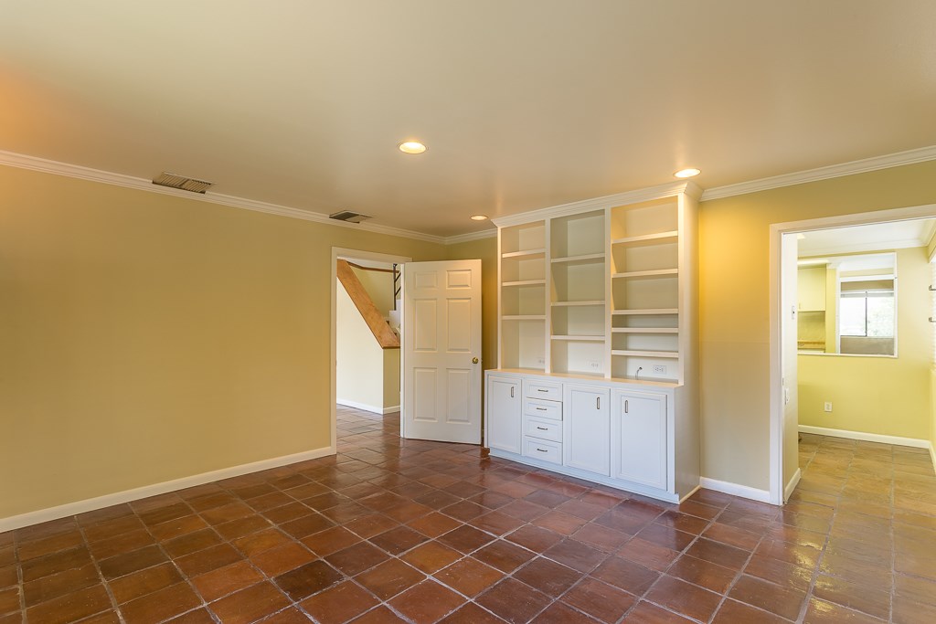 2349 Albans Road, Unit 2 Houston, TX 77005 - Photo 12 of 25 Dining/flex room features warm tile flooring, built-in shelving with cabinets, recessed lighting, and neutral walls, offering a cozy and functional space. Adjacent rooms are accessible through open doorways.