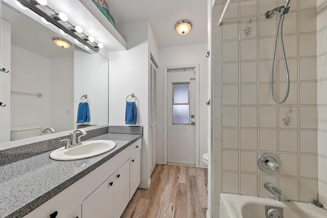 a bathroom with a granite countertop sink a mirror and shower
