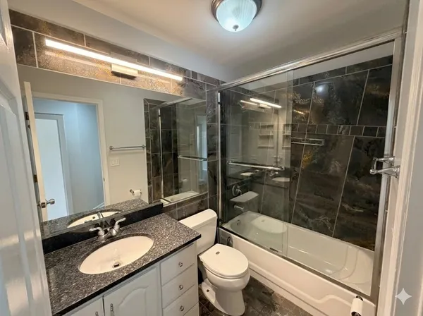 a bathroom with a granite countertop sink toilet mirror and shower