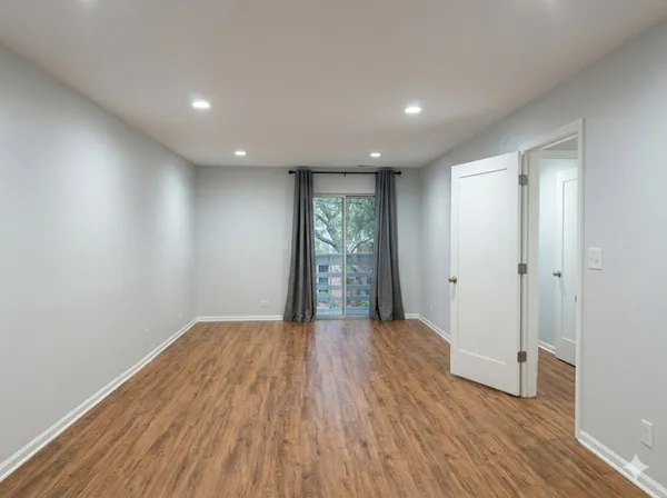 a view of an empty room with wooden floor and window