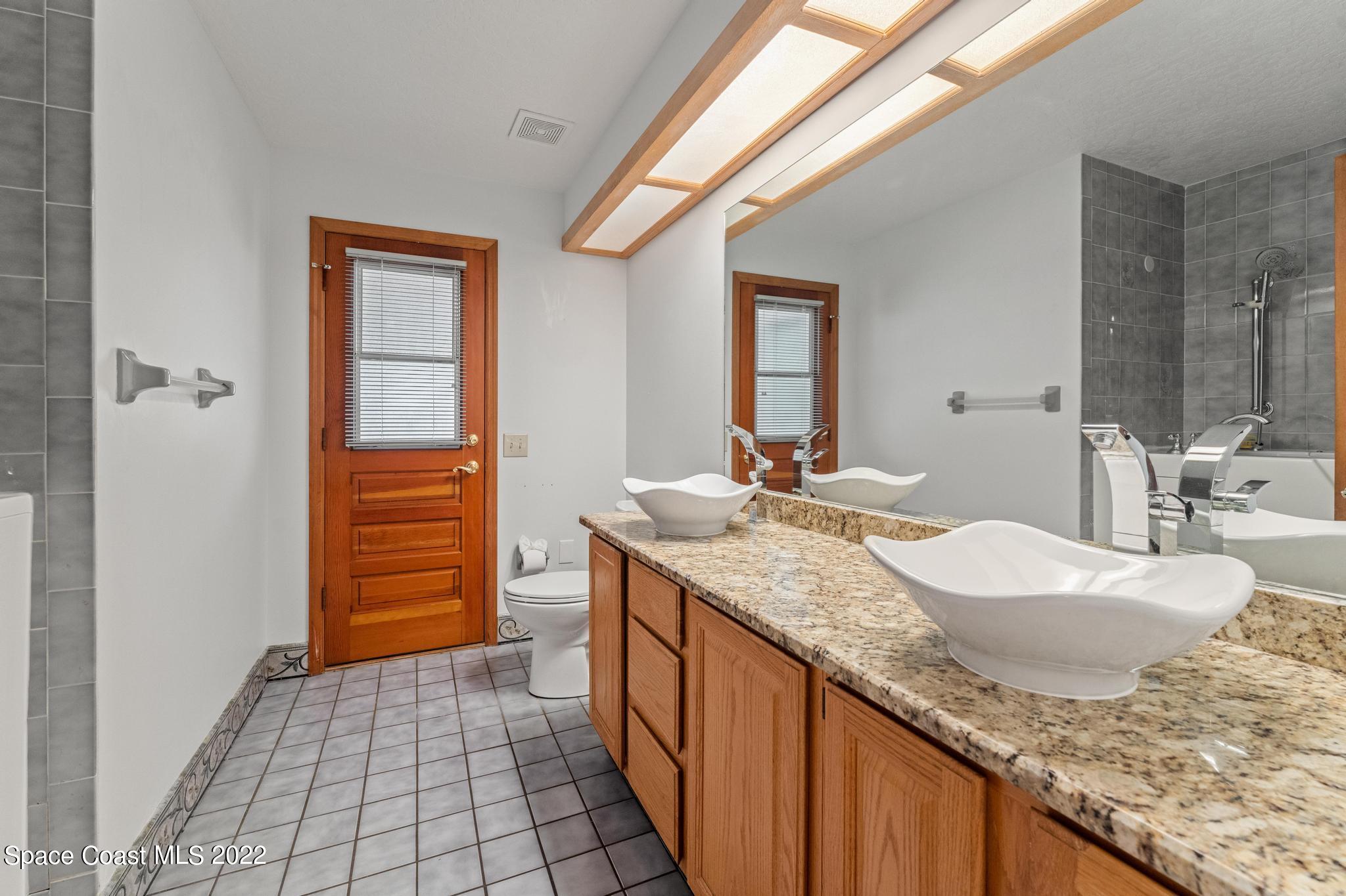 588 Peregrine Drive Indialantic, FL 32903 - Photo 12 of 23 a bathroom with a granite countertop sink and a mirror