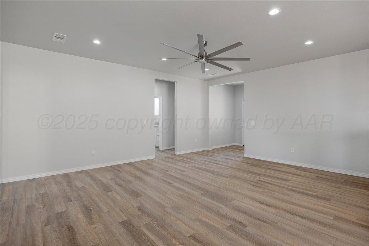 4204 Beacon Road Amarillo, TX 79118 - Photo 5 of 19 an empty room with wooden floor ceiling fan and windows
