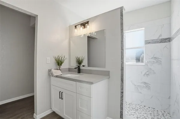 a bathroom with a granite countertop sink a mirror and shower