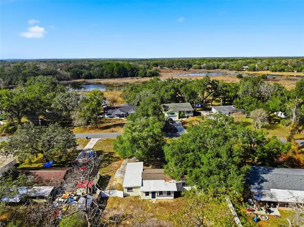 an aerial view of residential house with outdoor space and trees all around