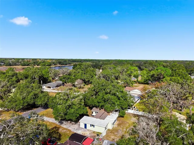 an aerial view of residential house with outdoor space and trees all around