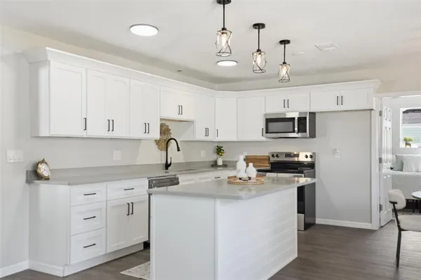 a kitchen with kitchen island granite countertop a sink a stove a refrigerator and white cabinets