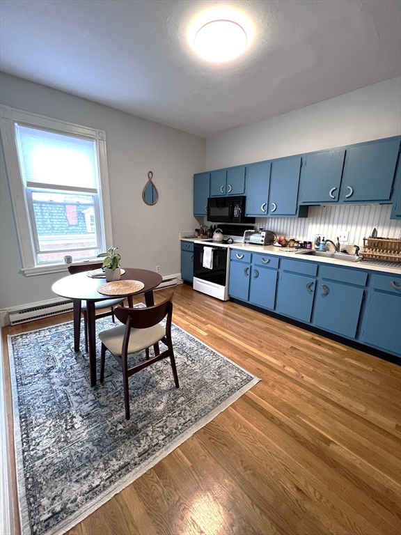 167 M Street, Unit 3F Boston, MA 02127 - Photo 4 of 7 a open kitchen with stainless steel appliances granite countertop a stove top oven a sink dishwasher a dining table and chairs with wooden floor
