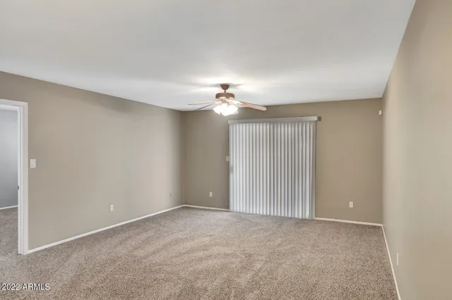 an empty room with a window and a fan