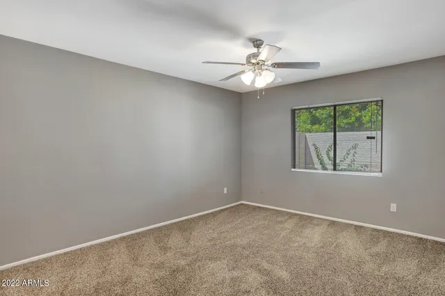 an empty room with a window and a fan