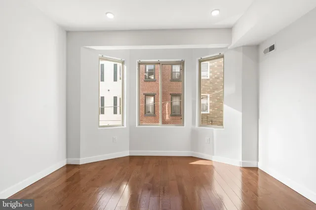 an empty room with wooden floor and windows