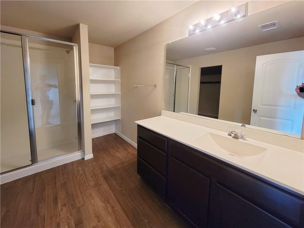 11924 Riparian Road Manor, TX 78653 - Photo 8 of 14 Full bathroom with vanity, a stall shower, dark wood-style floors, and a spacious closet