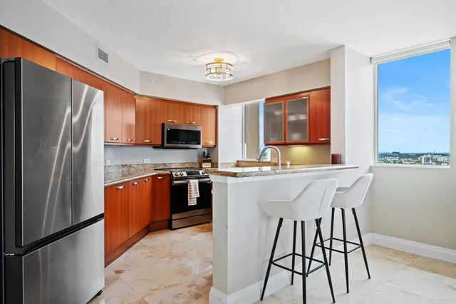 a kitchen with stainless steel appliances granite countertop a refrigerator a stove top oven a sink dishwasher and a refrigerator with wooden floor