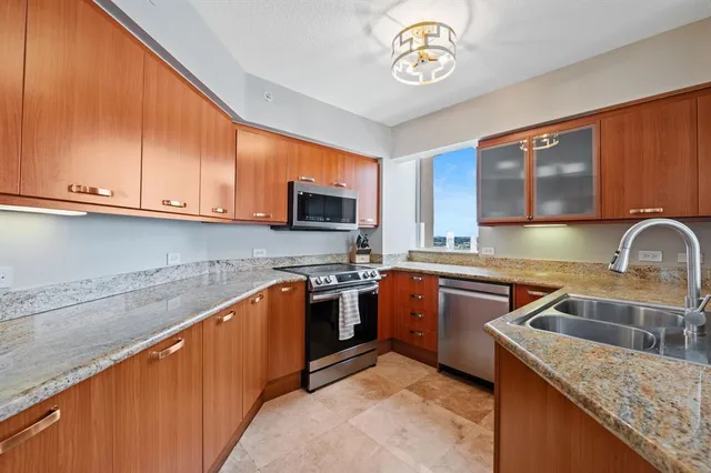 a kitchen with stainless steel appliances granite countertop a sink dishwasher stove and microwave with wooden cabinets