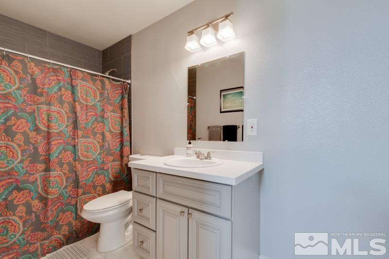 1695 Lander Street Reno, NV 89509 - Photo 19 of 38 a bathroom with a sink a toilet a mirror and shower curtain