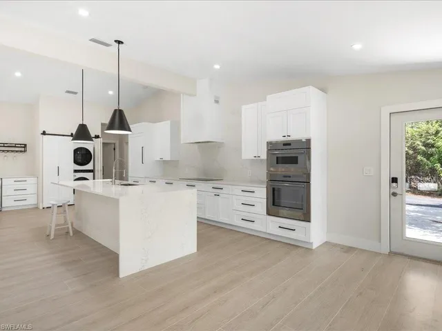 a kitchen with stainless steel appliances kitchen island wooden floors and white cabinets
