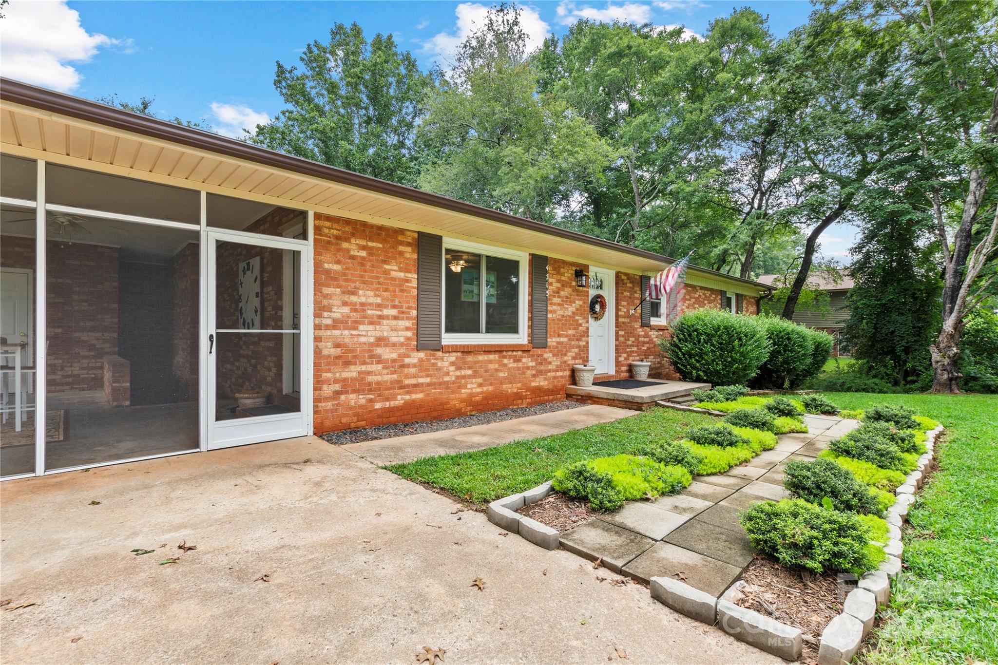 a backyard of a house with plants and large tree