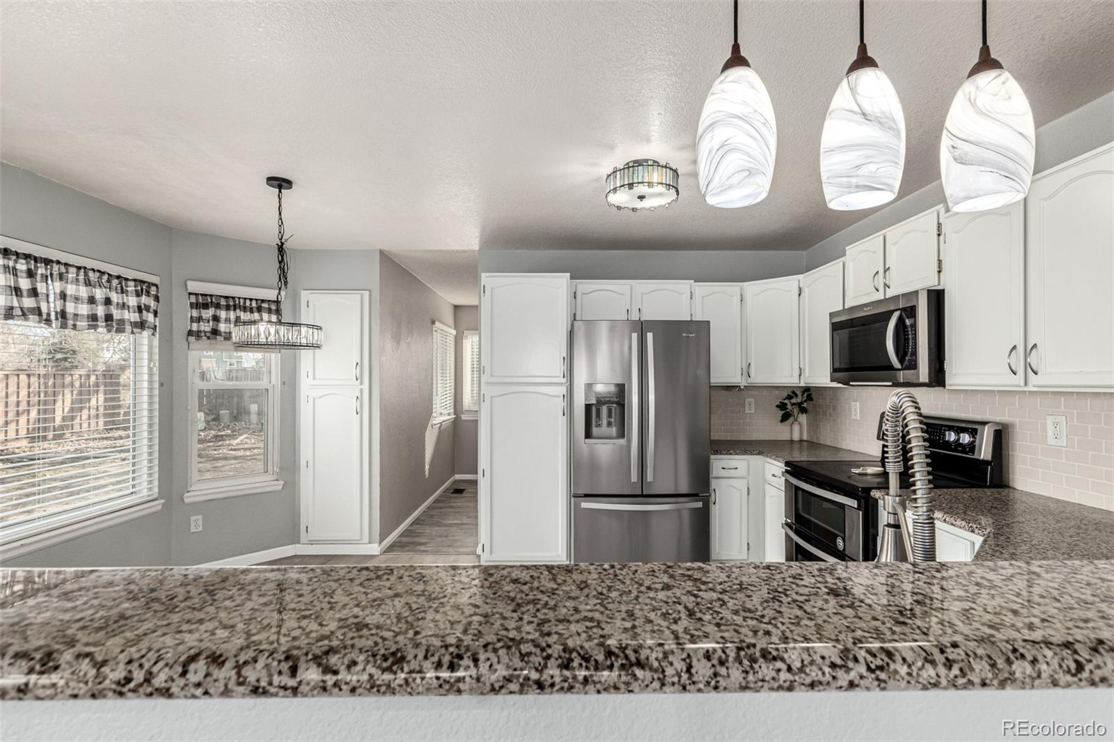 3623 West Rosewalk Circle Highlands Ranch, CO 80129 - Photo 14 of 44 a kitchen with stainless steel appliances kitchen island granite countertop a refrigerator oven a sink and dishwasher