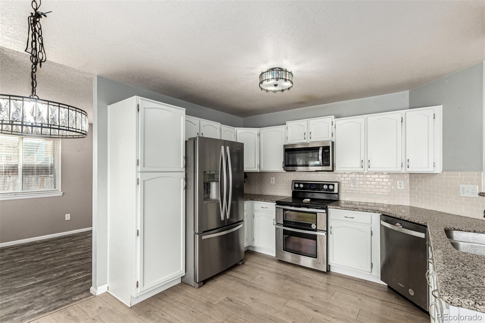 3623 West Rosewalk Circle Highlands Ranch, CO 80129 - Photo 16 of 44 a kitchen with stainless steel appliances a refrigerator a stove a sink and white cabinets