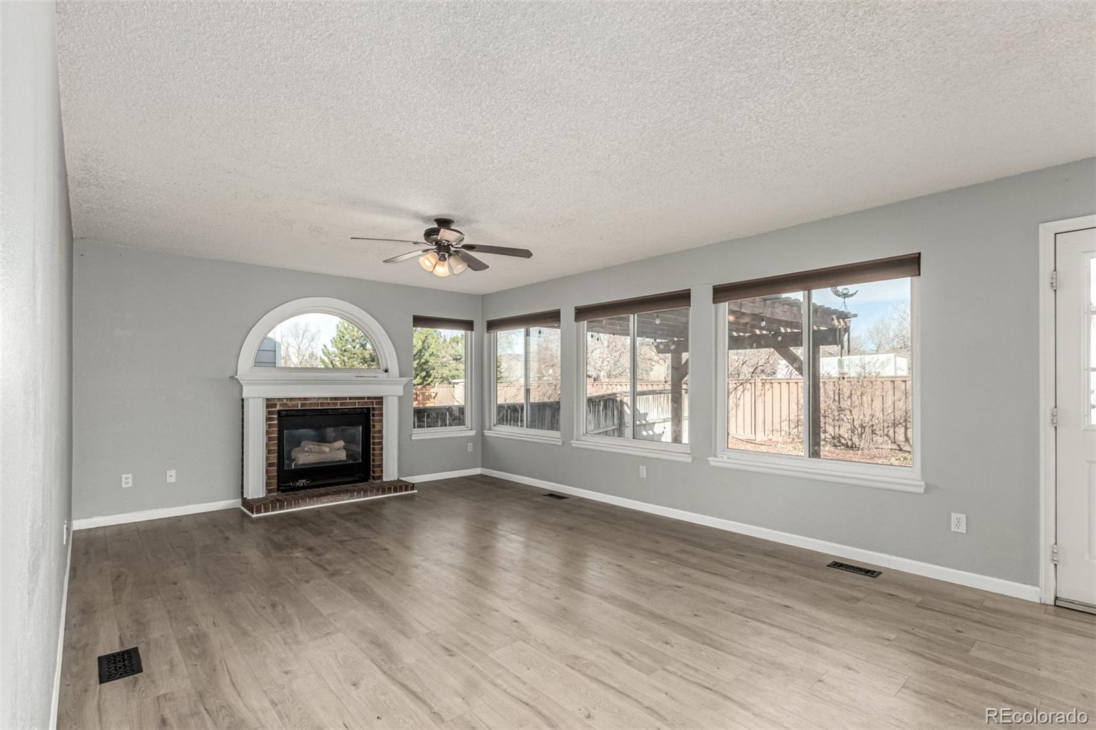 3623 West Rosewalk Circle Highlands Ranch, CO 80129 - Photo 8 of 44 an empty room with windows fireplace and wooden floor