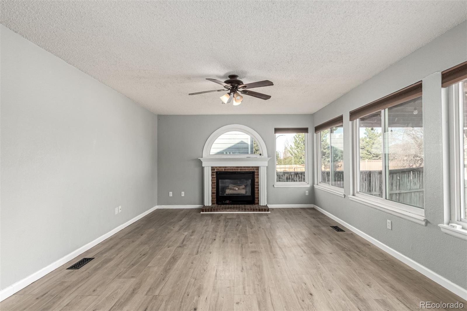 3623 West Rosewalk Circle Highlands Ranch, CO 80129 - Photo 9 of 44 wooden floor fireplace and windows in an empty room