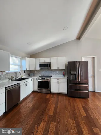 a kitchen with stainless steel appliances and wooden floor