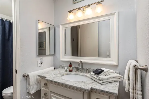 a bathroom with a granite countertop sink vanity mirror and toilet